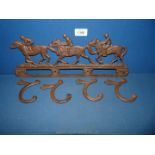 A cast iron coat hook, three horses/jockeys.