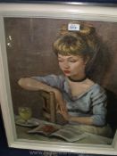 A framed Print of a young lady sitting at a table reading a book, 24'' x 28''.