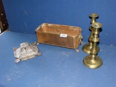 A copper planter with a pair of brass candlesticks and an ornate brass inkwell with ceramic well.