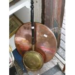 A copper and brass warming pan along with a round copper table top.