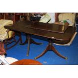 Dining table having extra central leaf standing on two tripod pedestal legs,