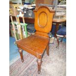 A late Victorian Oak hall Chair having a solid seat tapering turned and fluted front legs,
