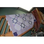 A hand-made Patchwork Quilt in purple, lilac & cream.