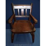 An Elm seated dark stained child's Armchair with arms having slots for a clip-on integral