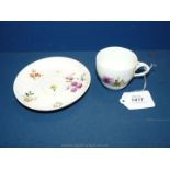 A 1750's Meissen cup and saucer with entwined leaf form handle and painted with deutsche blumen.