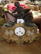 A metal cased Mantel Clock having a part gold and part black finished case surmounted by a kneeling