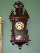 A dark wood cased wall clock with an eagle pediment and Acanthus leaf detail to the Roman style