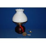 A red glass Oil Lamp with white shade, 13'' tall.