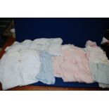 A quantity of vintage baby clothes including cotton night dresses and pink summer dresses.