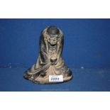 An oriental patinated metal figure of a balding beggar sitting cross legged with empty bowl in hand,