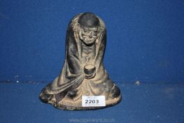An oriental patinated metal figure of a balding beggar sitting cross legged with empty bowl in hand,