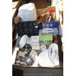 Two boxes of various kitchen cutlery, muffin tins, can opener, etc.