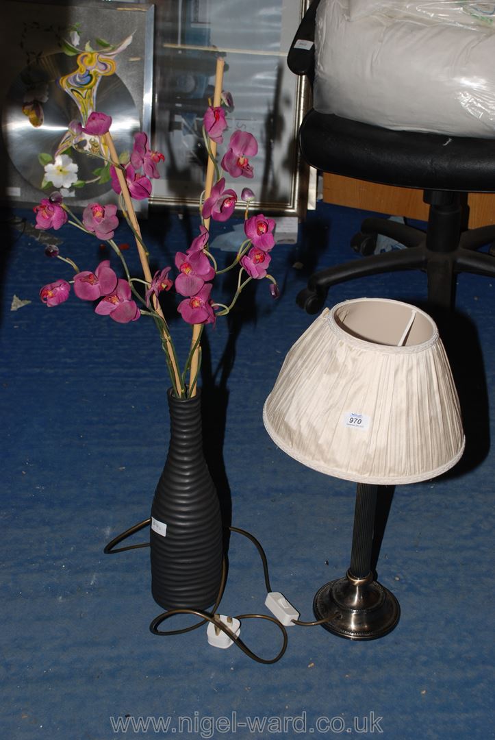 A table lamp and vase with artificial flowers.