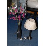 A table lamp and vase with artificial flowers.