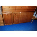 A teak style four drawer two cupboard dining unit top drawer having cutlery drawer.
