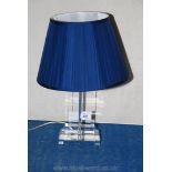 A contemporary glass table lamp with blue shade.