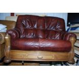 A two seat leather sofa on a wooden frame with drawer to base.