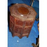 An octagonal carved hardwood table on folding stand.