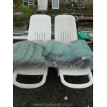 Pair of plastic sun loungers with set of cushions.