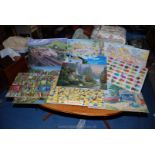 A quantity of 12 made up jigsaw puzzles having cling film covers.