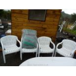 Four plastic patio chairs with cushions