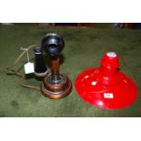 A candlestick style telephone and red metal lamp shade.