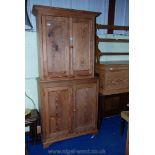 A pine kitchen cupboard with two shelves to the top and one and a half shelves to the bottom,