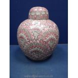 A large oriental ginger jar with embossed pink lotus pattern. 13" tall.