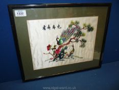 A framed silk embroidery of Peacocks in a tree.