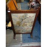 An Oak framed Firescreen having a fluted top rail and with an inset tapestry depicting a thatched