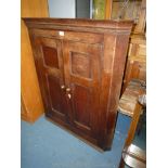A Georgian Oak wall-hanging Corner Cupboard having a pair of two panelled doors and with a