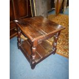 A heavy dark Oak square occasional Table standing on turned legs united by a lower shelf,