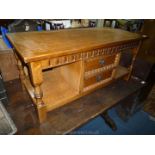 A medium oak finished Coffee Table on turned legs and having a central section with two short