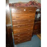 A dark Oak Tallboy of eight short drawers having rectangular oak handles,