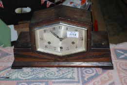 A dark Oak finished Art Deco style mantel Clock having a compressed hexagonal face with Arabic