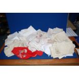 A box of mixed embroidered Portuguese serviettes, handkerchiefs, red bag containing crochet work,