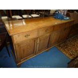 A contemporary mid oak sideboard having faux frieze drawers with pierced back plate brass drop