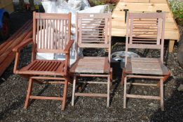 A pair of wooden garden chairs plus one other.