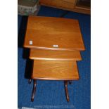 A set of three teak style nest of tables.