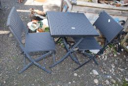 A plastic rattan effect bistro table and two chairs