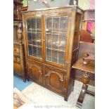 A dark Oak Priory style leaded glazed doored Bookcase on Cupboard having a stylised floral/foliage