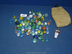 A quantity of miscellaneous small and large marbles, together with a pea whistle.