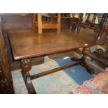 A refectory type dark Oak Dining Table standing on turned end supports and with central stretcher,