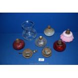 A quantity of oil lamp fittings including cranberry glass,