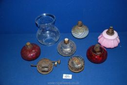 A quantity of oil lamp fittings including cranberry glass,