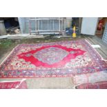 A bordered patterned and fringed Rug with a purple floral centre with red surround and floral