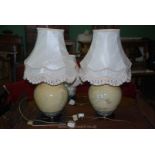 A pair of cream lamps with wooden bases, blue and green border and decorated with flowers,