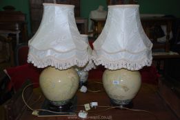 A pair of cream lamps with wooden bases, blue and green border and decorated with flowers,