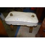 A cream upholstered seated folding Camel Saddle with brass frame cups and plaques,