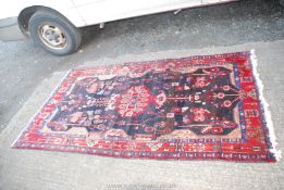 A bordered patterned and fringed Rug in red, blue and black with geometric designs, 48" x 89".